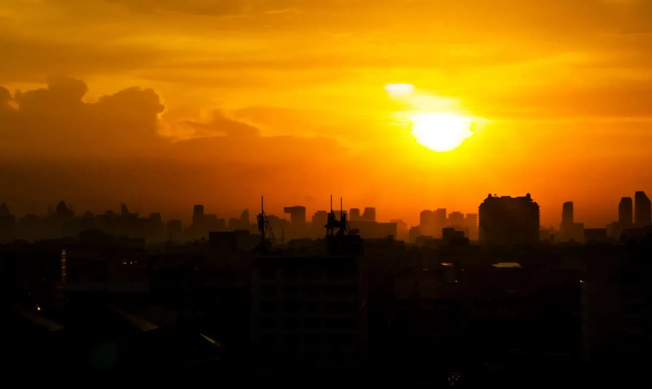 Um entardecer quente e abafado, com o sol se pondo no horizonte
